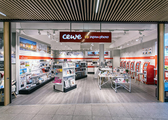 Butikklokale til CEWE Japan Photo med lyst interiør, hyller med fotoprodukter og fotokiosker på høyre side Butikklokale til CEWE Japan Photo med lyst interiør, hyller med fotoprodukter og fotokiosker på høyre side