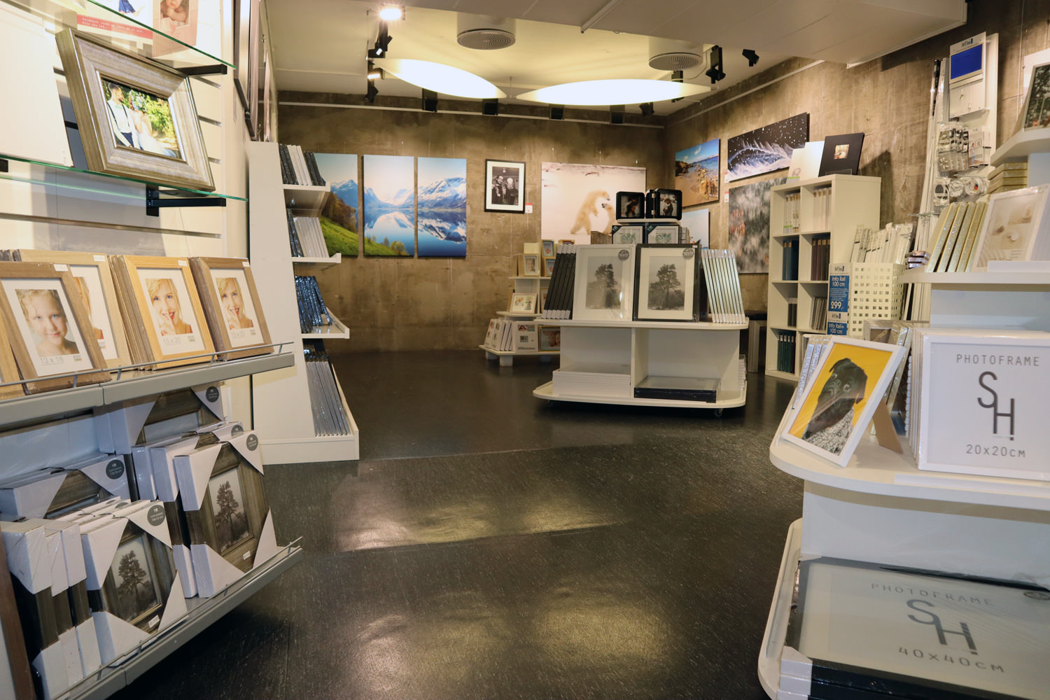 En lys og moderne butikk som viser en rekke bilderammer og fotokunst, med hyller fylt med forskjellige design og størrelser