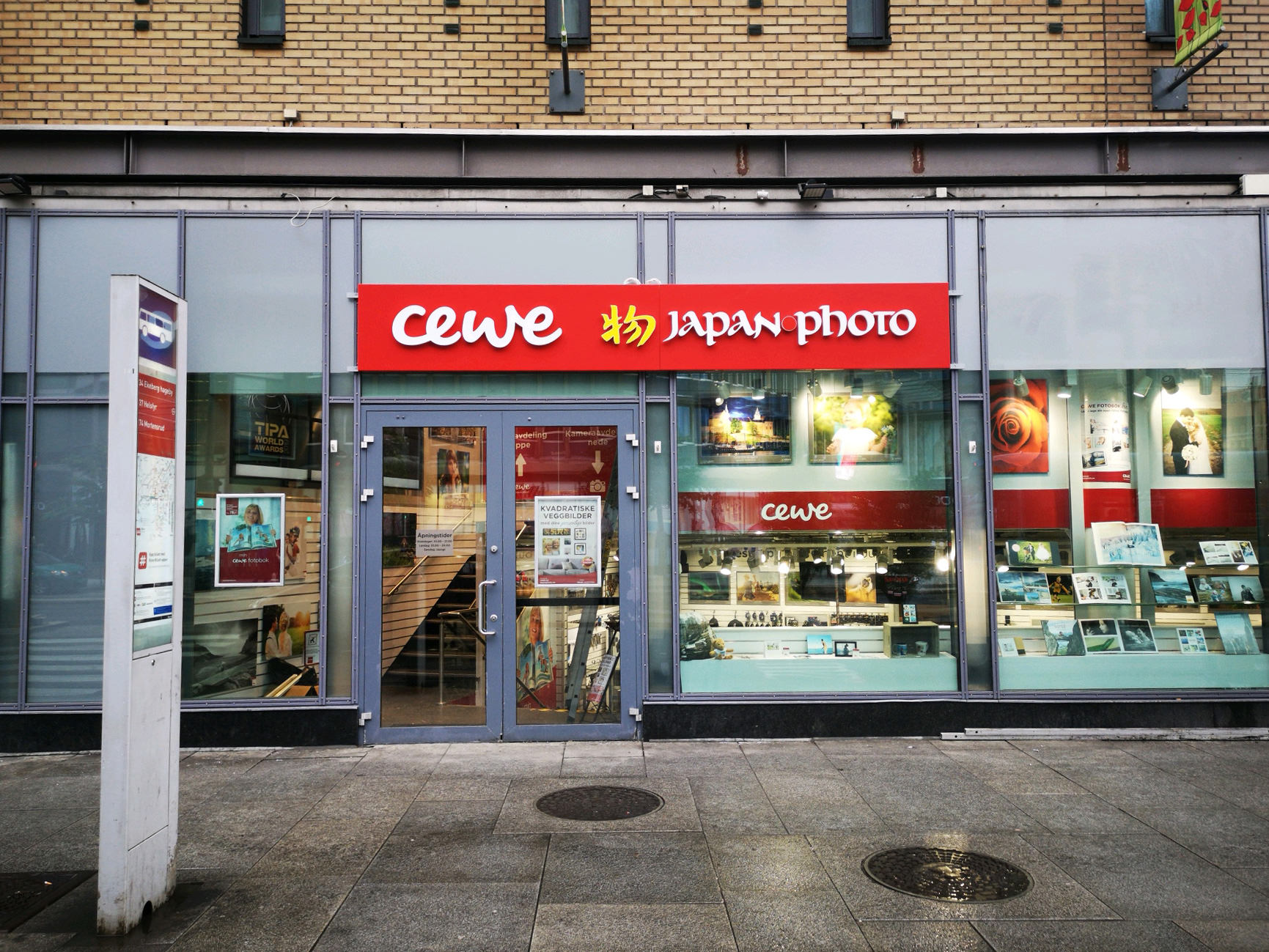 Butikklokalet til CEWE Japan Photo med store glassvinduer, utstillingsprodukter og en rød logo over inngangsdøren.