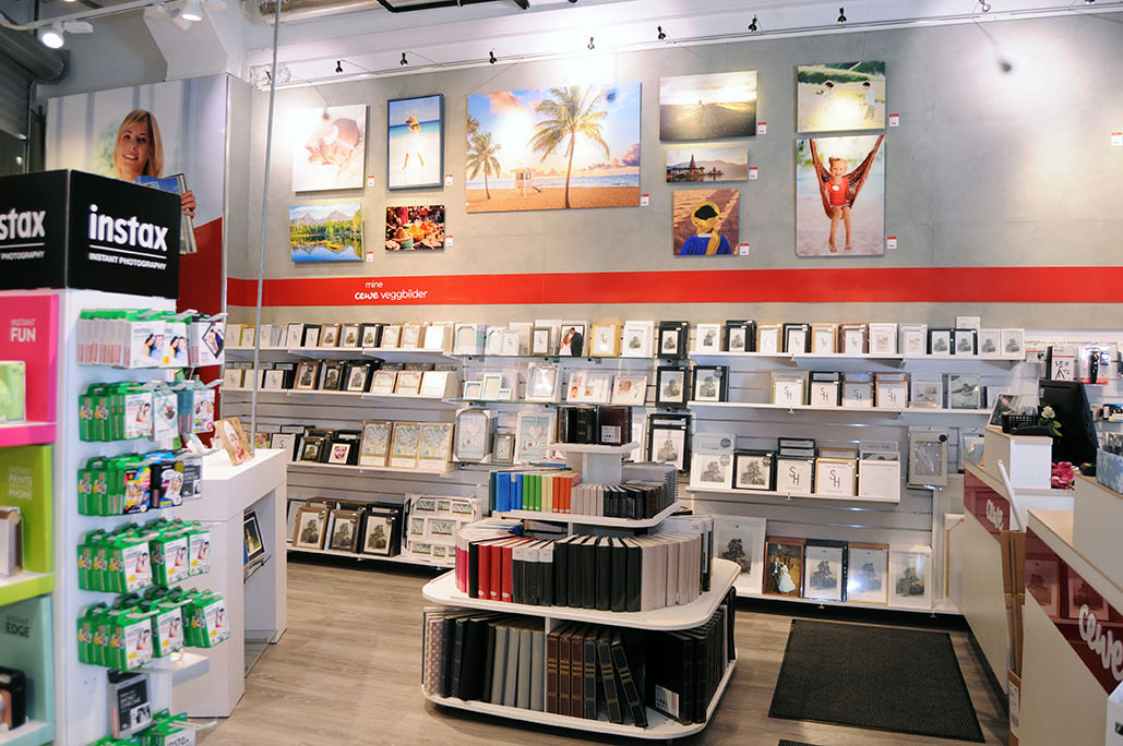 Butikkinteriør med veggdekorasjoner, rammer og fotobøker utstilt lyst og innbydende Butikkinteriør med veggdekorasjoner, rammer og fotobøker utstilt lyst og innbydende