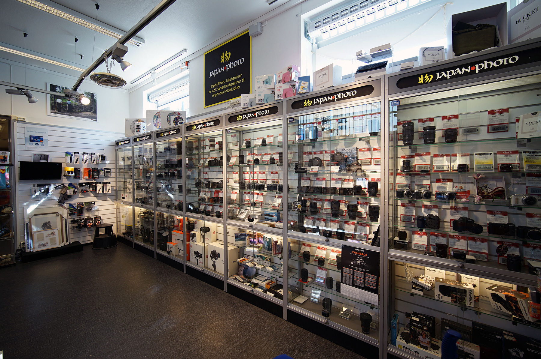 Et butikkinteriør med opplyste glasskap som viser kameraer, objektiver og fototilbehør fra Japan Photo