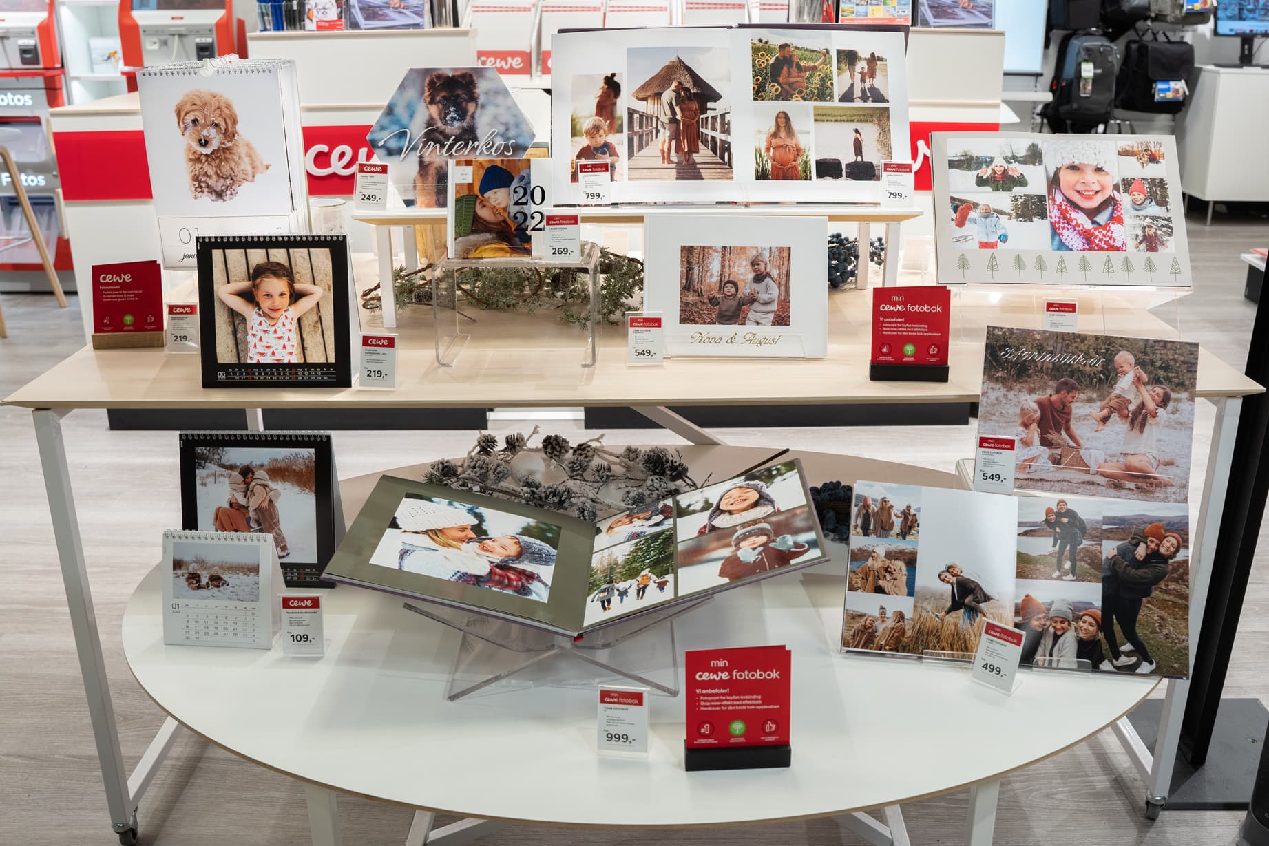 Utstilling med ulike fotoprodukter, inkludert kalendere, fotobøker og veggdekor med personlige bilder.
