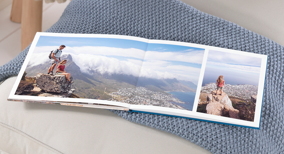 Fotobok med fargerike bilder av turpar på fjelltur med havutsikt og bylandskap i bakgrunnen