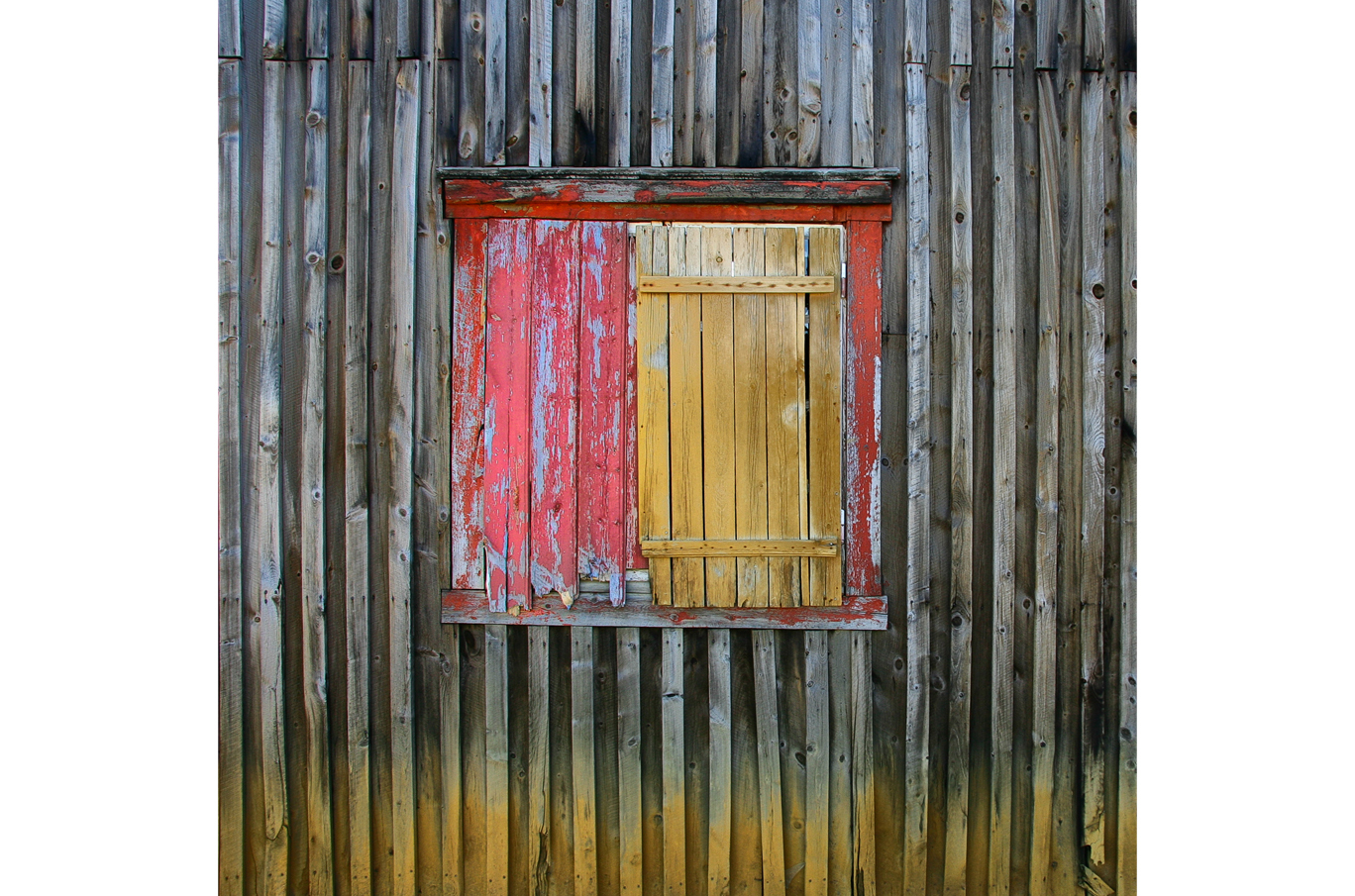 Værvegg med grå trepaneler, et slitt rødmalt vinduskarmer og en gulmalt, lukket skodde Værvegg med grå trepaneler, et slitt rødmalt vinduskarmer og en gulmalt, lukket skodde