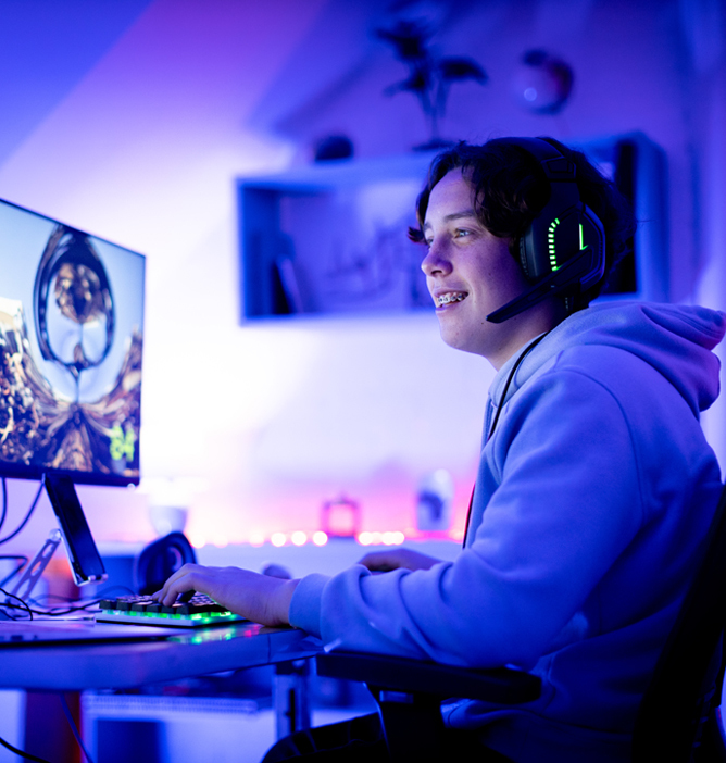 Person som spiller videospill på PC i et opplyst rom med neonfargede lys