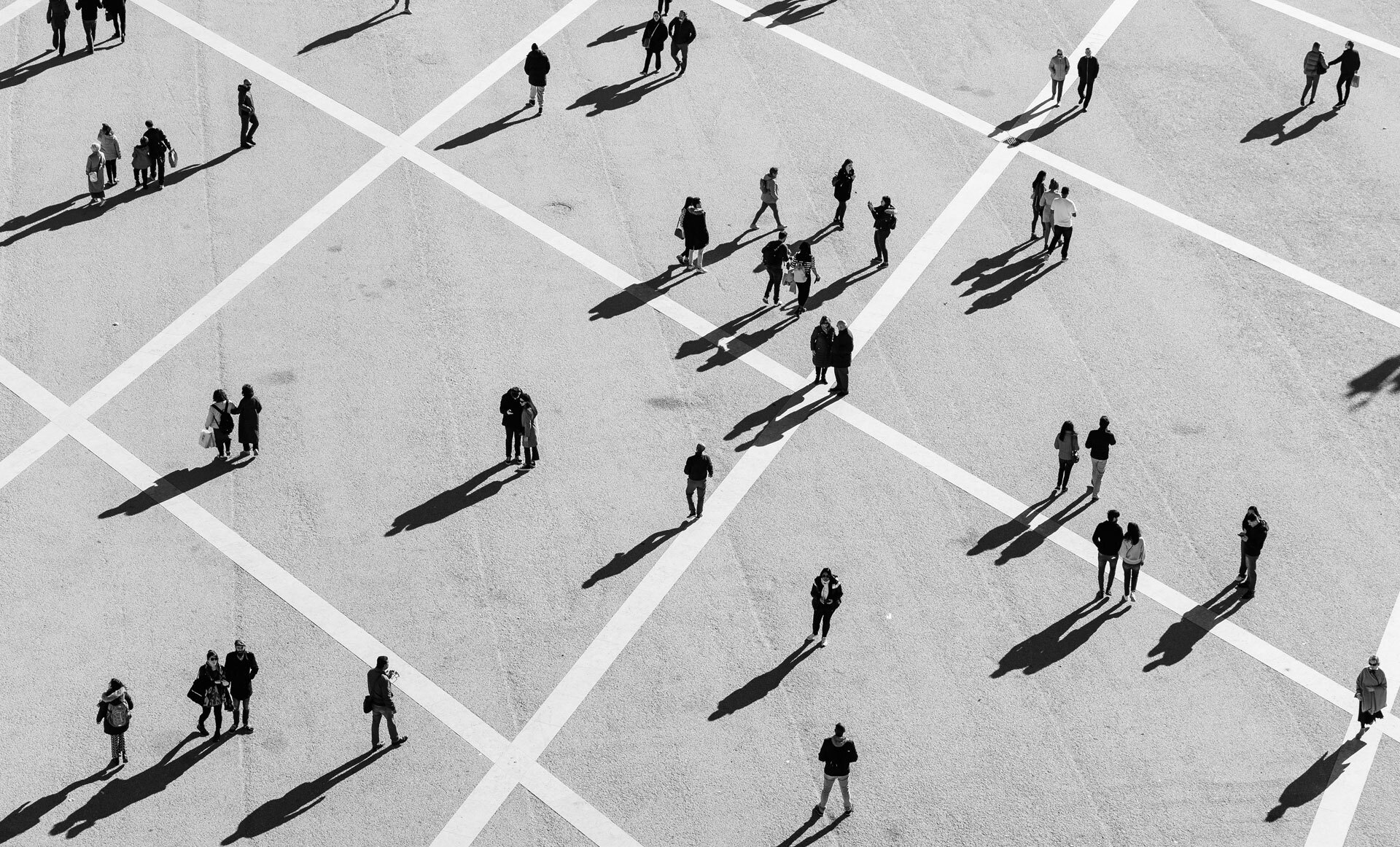 Mennesker som går og står spredt på et stort, rutete torg.