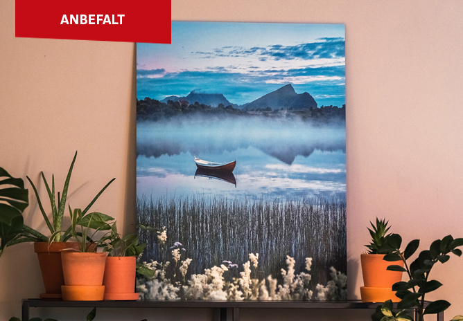 Et bilde av et lerret med et vakkert landskapmotiv: en stille innsjø med et ensomt, rødt robåt i midten, omgitt av siv og fjell i bakgrunnen under en kveldshimmel