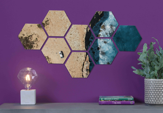Hexagonale bilder på lilla vegg viser en kystlinje med sand, klipper og blått hav