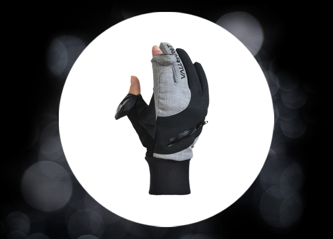 En grå og svart hanske med glidelås og ribbestrikket mansjett, vist mot en lys sirkel med mørk bakgrunn