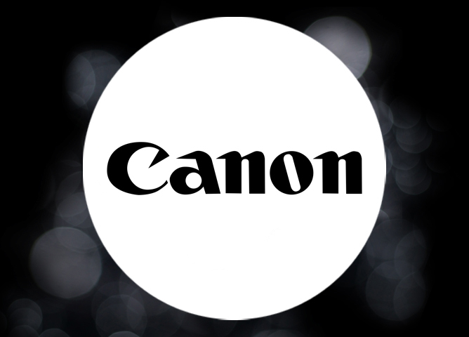 Canon-logo på en hvit sirkel med en bakgrunn av uskarpe lysbokeh-punkter