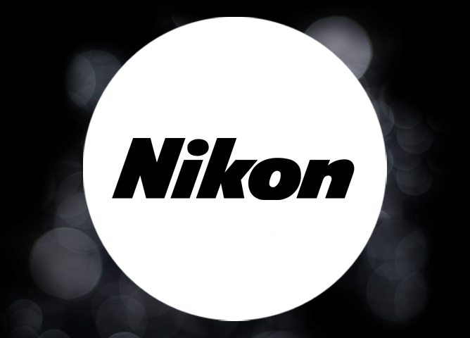 Nikon-logo med hvit sirkel omringet av uklare, mørke lysbokeh