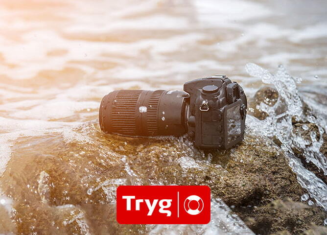 Kamera med telelinse ligger på en våt stein i sjøen, omgitt av vannsprut i sollys