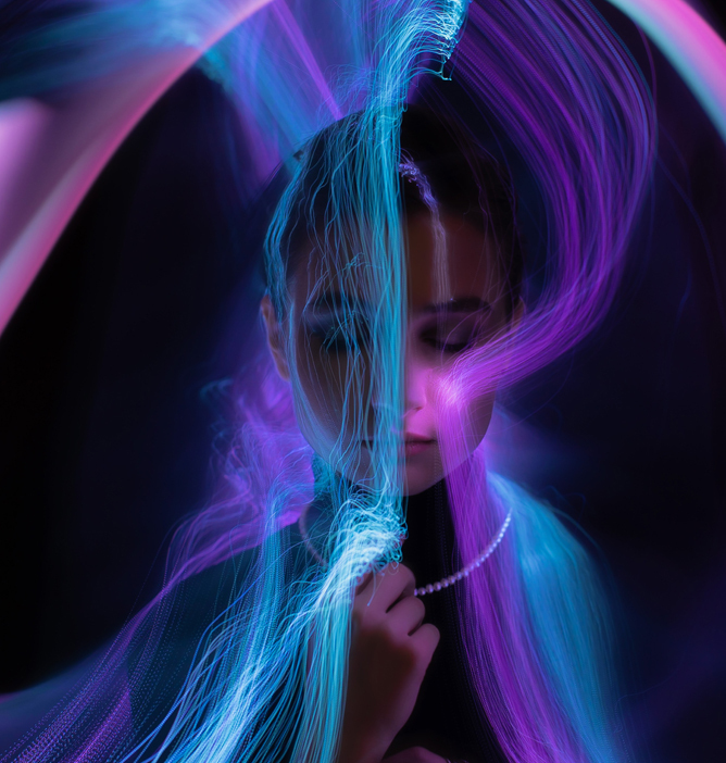 Neonlys i blått og lilla som danner flytende linjer mot en mørk bakgrunn.