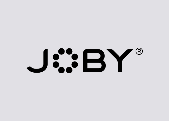 Joby-logo i svart med sirkulære prikker som danner en sirkel i bokstaven "O" på grå bakgrunn