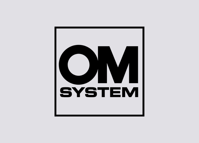Logoet til OM System med svart tekst på grå bakgrunn