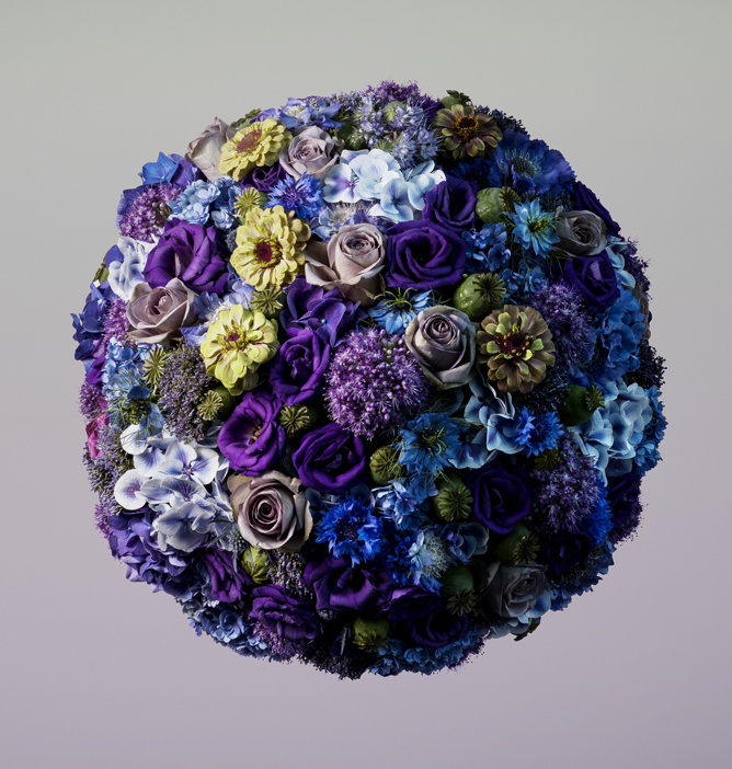 En rundt bukett med lilla, blå, hvite og gule blomster i et harmonisk fargespekter