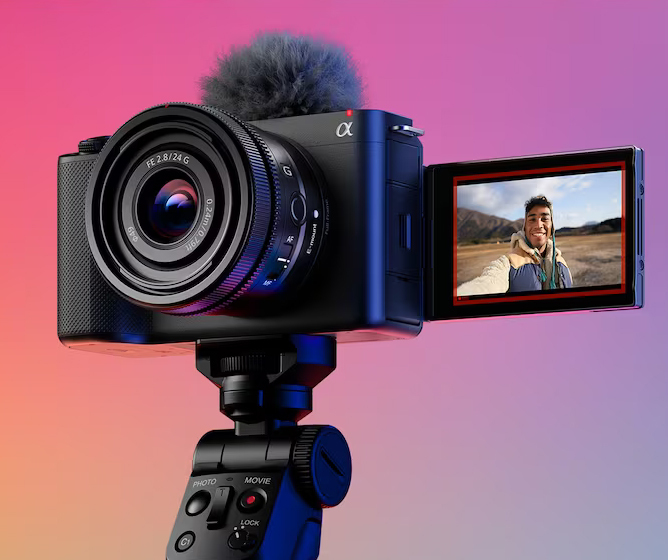 Kompaktkamera på stativ med dreibar skjerm som viser et bilde av landskap i bakgrunnen