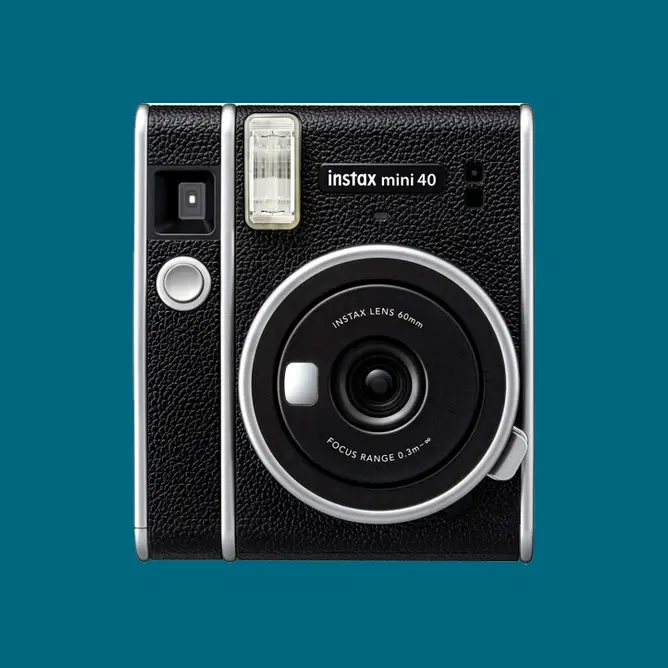 Kompaktkamera i retrodesign med svart lærtekstur, sølvdetaljer og et rundt objektiv i midten