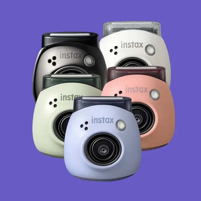 Fargerike Instax-kameraer i pastell- og nøytrale toner, gruppert mot en lilla bakgrunn