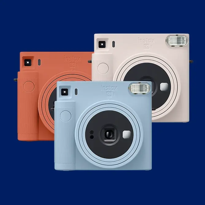 Tre polaroidkameraer i pastellfargene blå, hvit og oransje mot en mørk blå bakgrunn