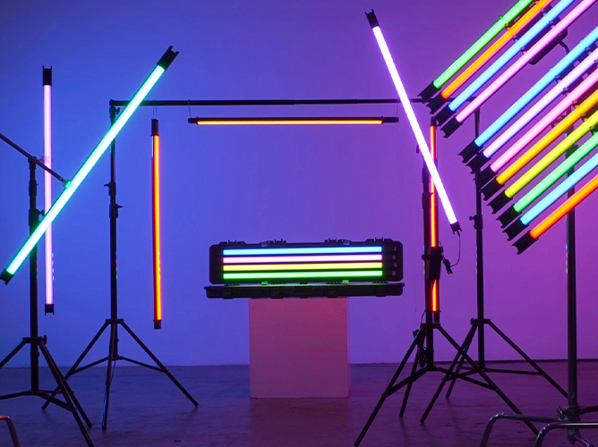 Fargerike lysrør i ulike neonfarger arrangert på stativer i et mørkt rom