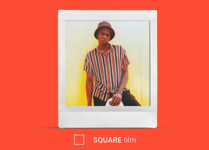 En person i stripete skjorte og hatt står foran en gul bakgrunn.