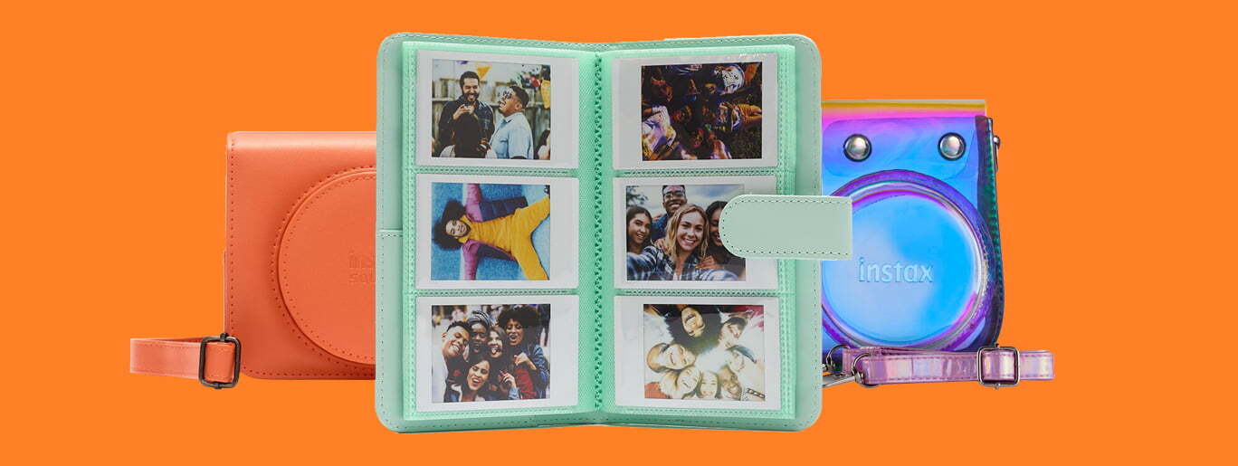 Mintgrønn fotoalbum med polaroidbilder, oransje veske og holografisk Instax-kameraveske mot oransje bakgrunn
