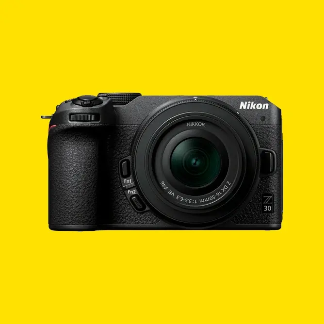 Svart Nikon Z30 speilløst kamera med en NIKKOR-linse mot en klar gul bakgrunn