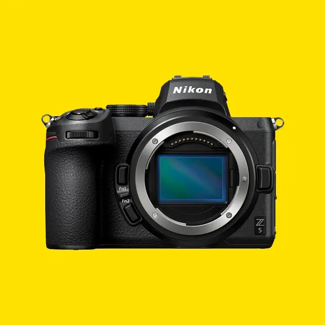 Speilløs kamera Nikon Z5 med svart kamerahus sett forfra på lys gul bakgrunn
