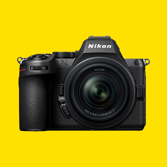 Nikon speilløst kamera med svart hus og NIKKOR-objektiv, sentrert på gul bakgrunn