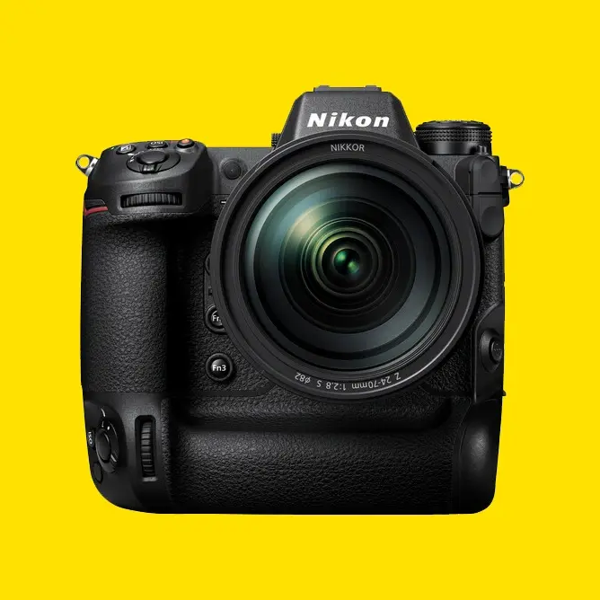 Nikon-kamera med stor linse, svart design og gul bakgrunn