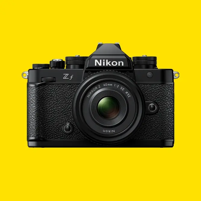 Sort kamera i retrodesign med Nikon-logo foran, mot en lys gul bakgrunn