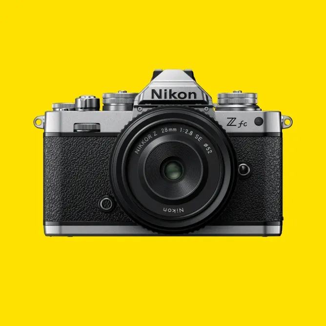 Klassisk Nikon Z fc kamera med rund linse, svart og sølv design på gul bakgrunn