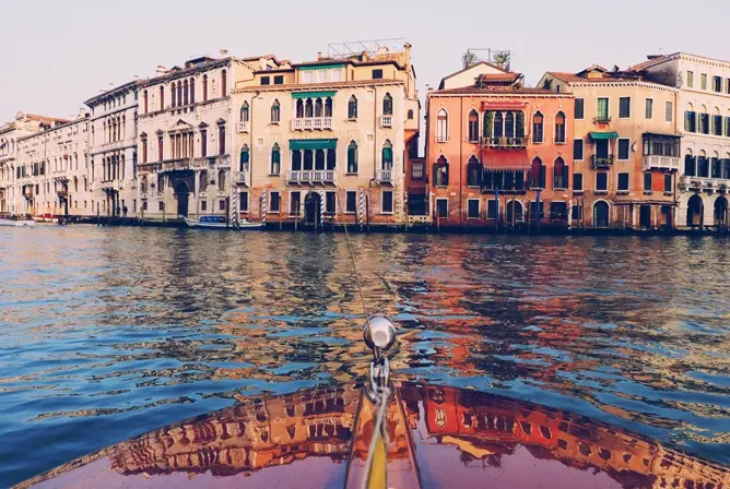 Spiss av trebåt med utsikt mot fargerike bygninger langs en kanal i Venezia Spiss av trebåt med utsikt mot fargerike bygninger langs en kanal i Venezia