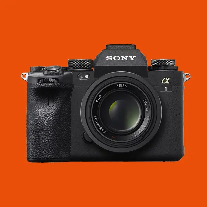 Sony speilreflekskamera med Zeiss-objektiv, sett forfra mot en oransje bakgrunn