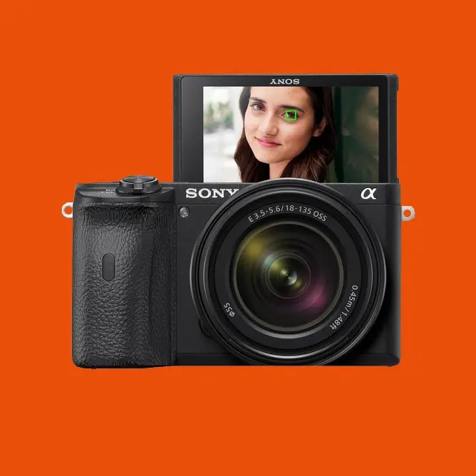 Sony digitalkamera med stort objektiv og vippbar skjerm, vist mot oransje bakgrunn