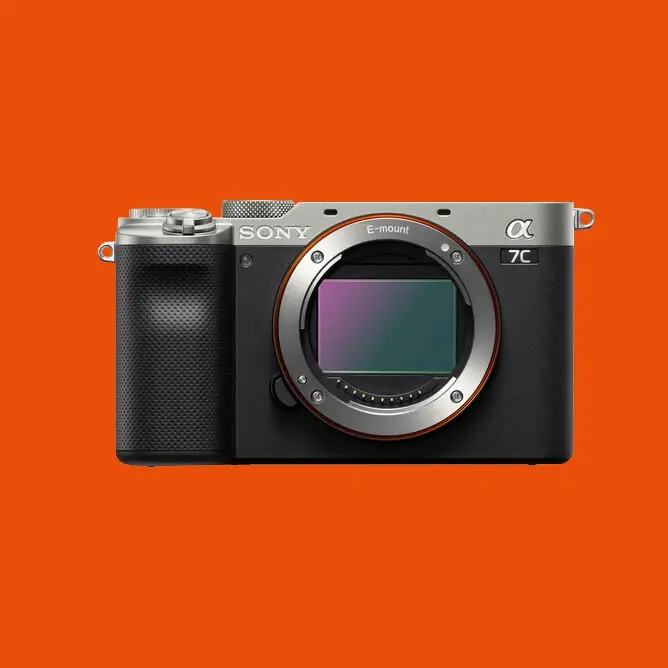 Sony Alpha 7C kamera uten objektiv, vist forfra mot oransje bakgrunn