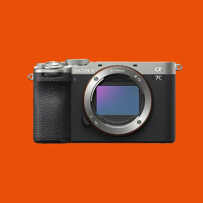 Sony Alpha 7C kamera uten objektiv, sett forfra med en oransje bakgrunn