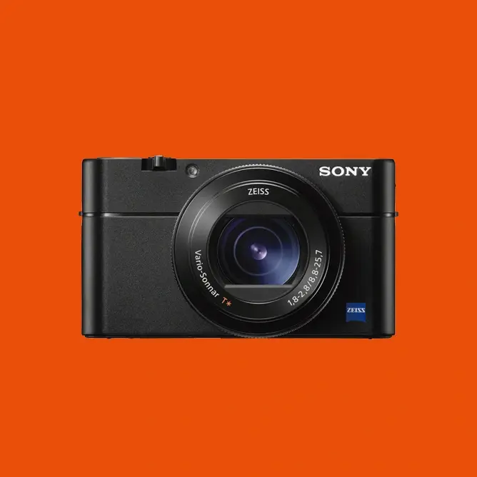 Svart Sony kompaktkamera med Zeiss-linse i sentrum, oransje bakgrunn