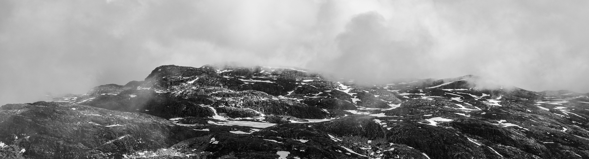 Skyet fjellandskap med steinete terreng og områder med snøflekker