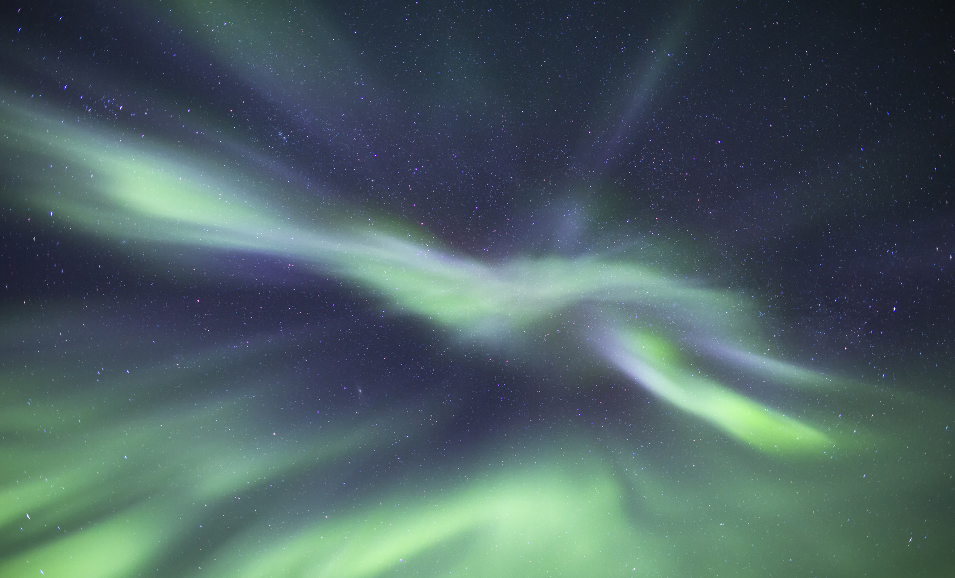 Grønn og lilla nordlys som danser over en stjerneklar nattehimmel