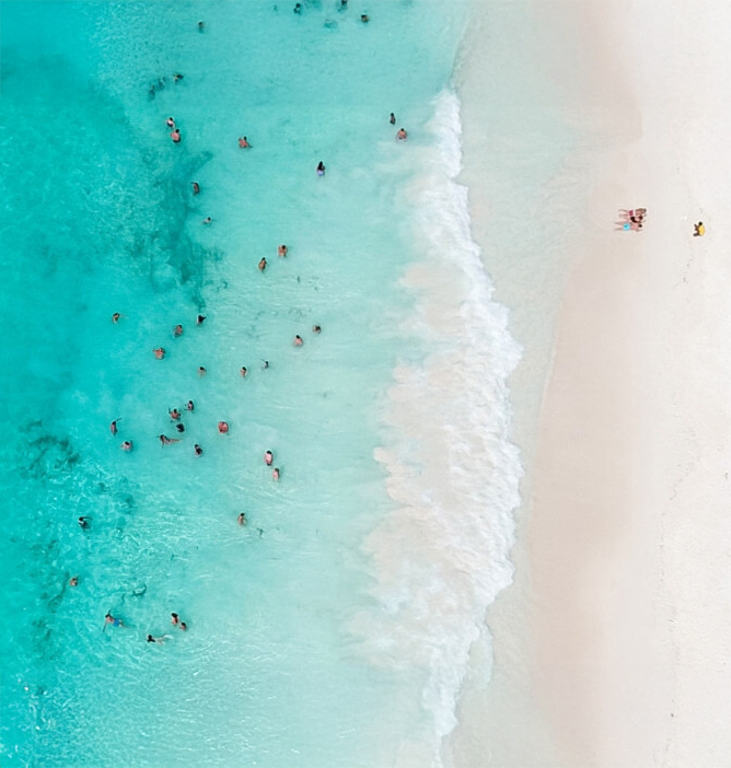 Luftfoto av turkist hav med badegjester nær en hvit sandstrand
