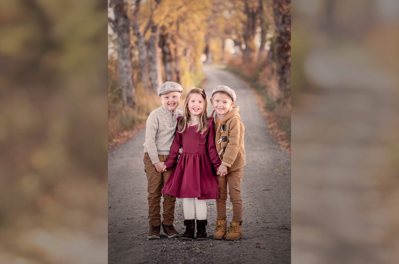Tre barn holder hender på en grusvei omgitt av høstfargede trær