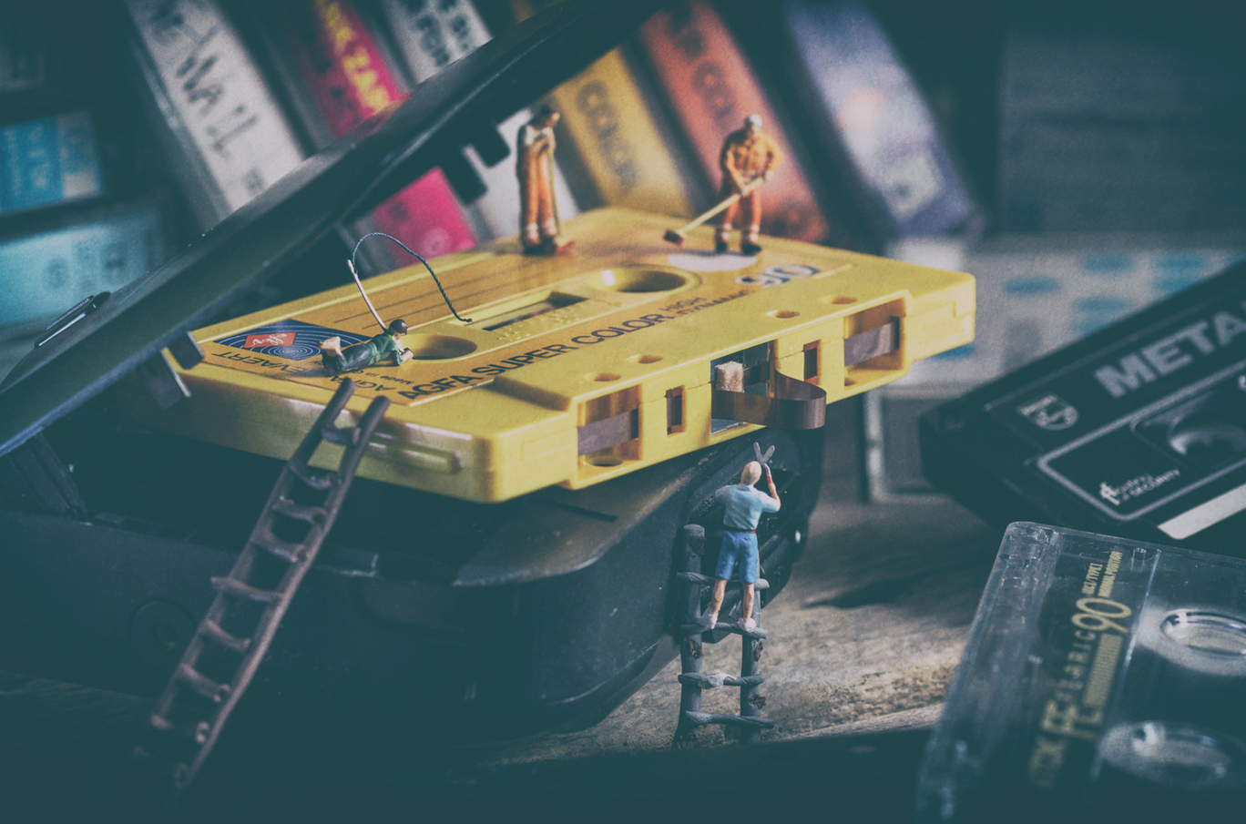 Miniatyrfigurer rengjør og reparerer en stor gul kassett med stiger og utstyr