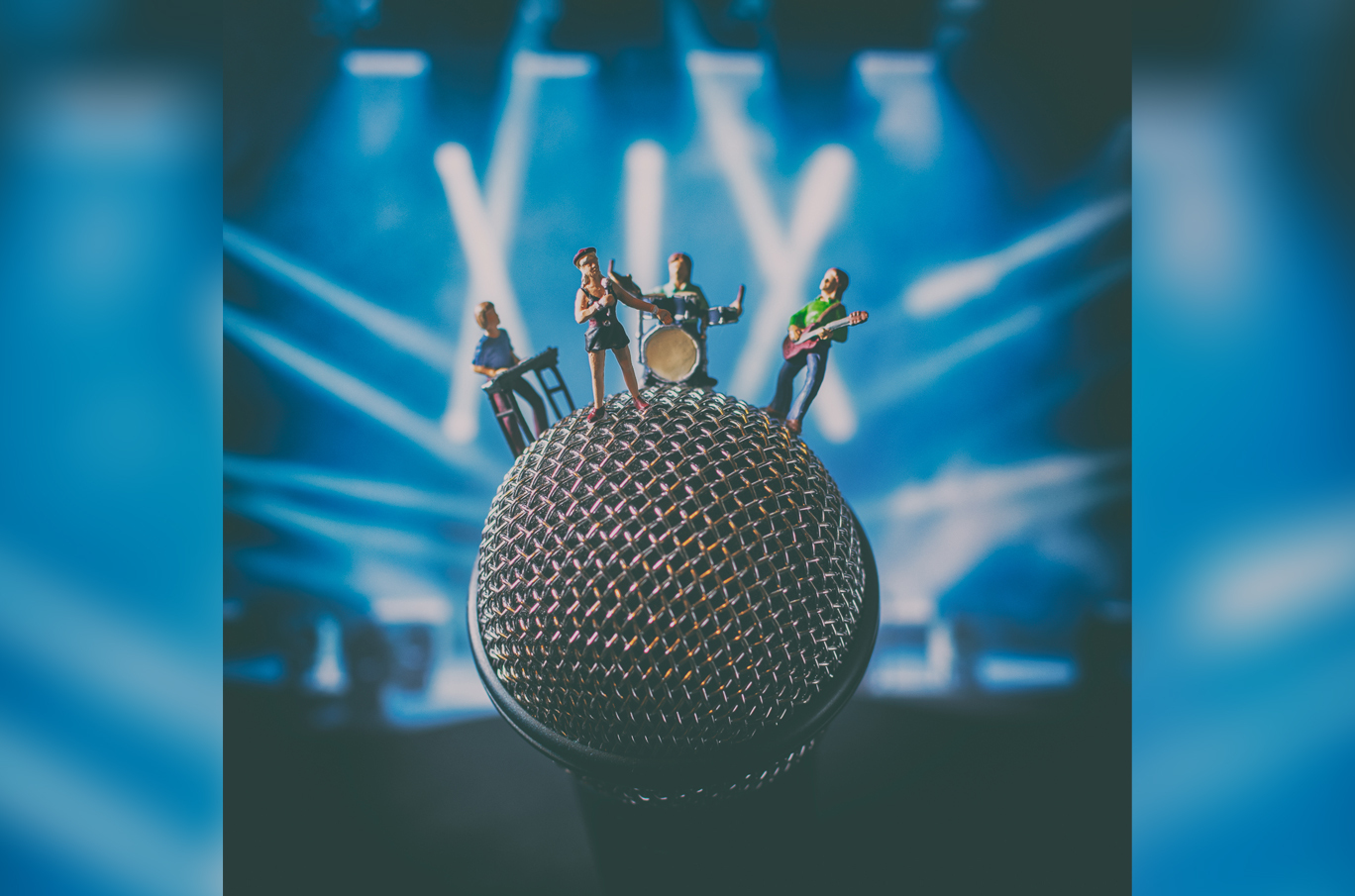 Små figurer av musikere som spiller instrumenter, plassert på toppen av en mikrofon