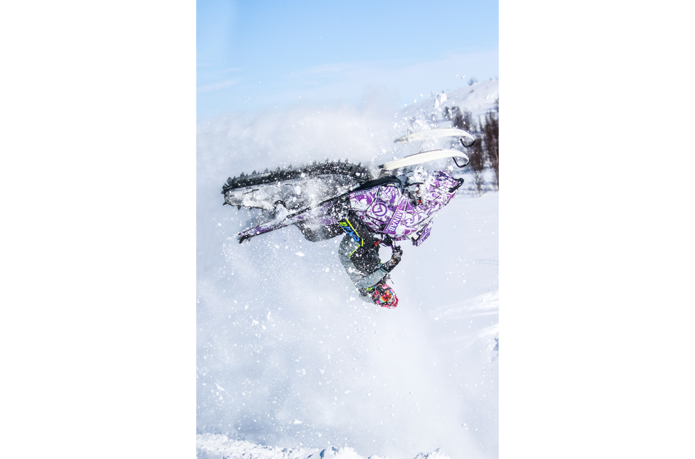 Mann utfører baklengs salto på snøscooter i luftig snølandskap