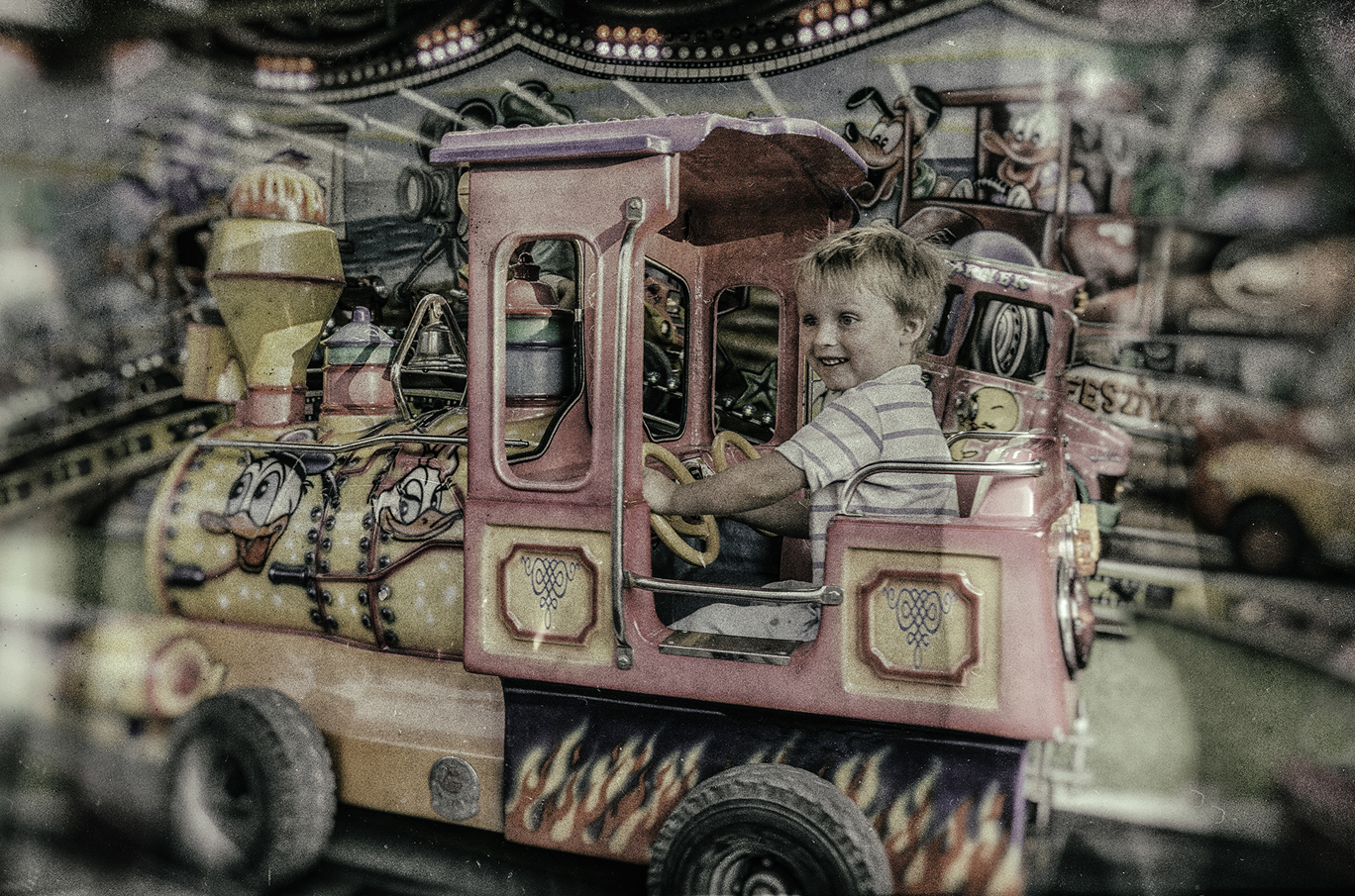 Barn som kjører en fargerik karuselltog med tegneseriefigurer og flammedesign