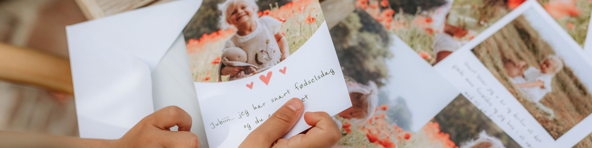 Et kort med håndskrevet tekst og røde hjerter holdes av en barnehånd, omgitt av bilder med blomsterenger i bakgrunnen