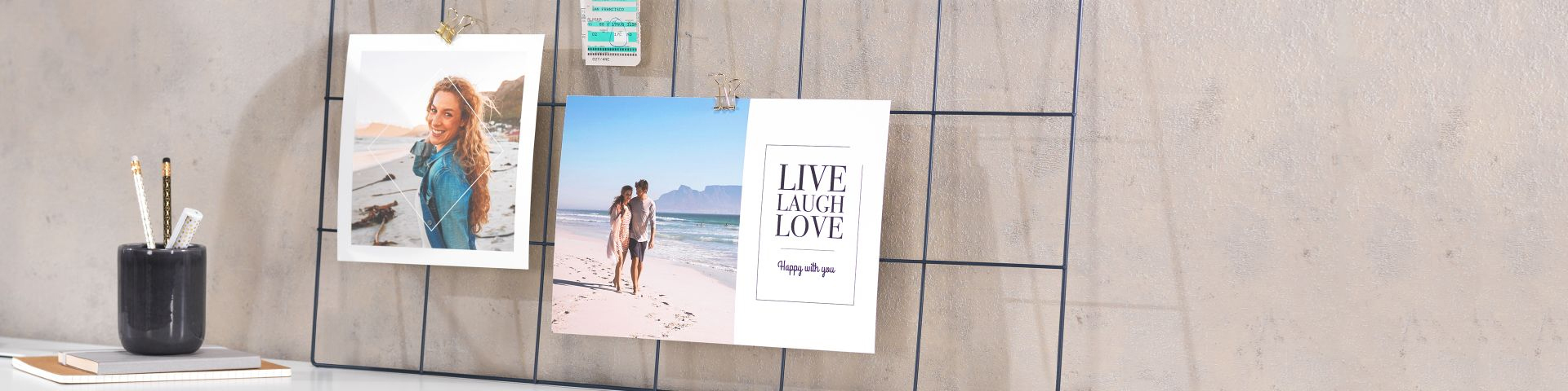 Tavle med bilder og kort, inkludert et strandbilde av et par og et kort med teksten "Live Laugh Love"
