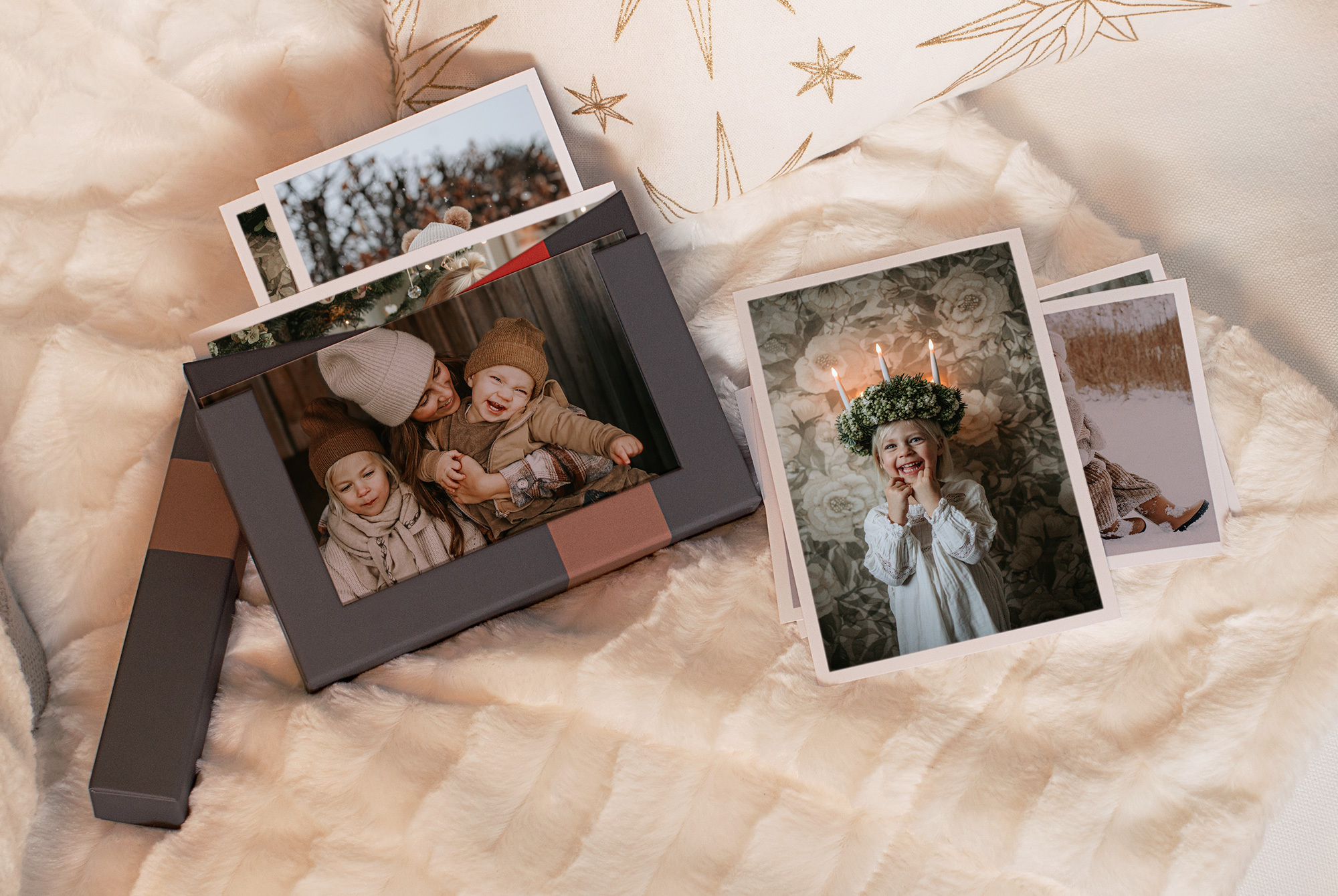 Fotobokser på en myk, lys pleddflate med utvalgte bilder synlig fra esken
